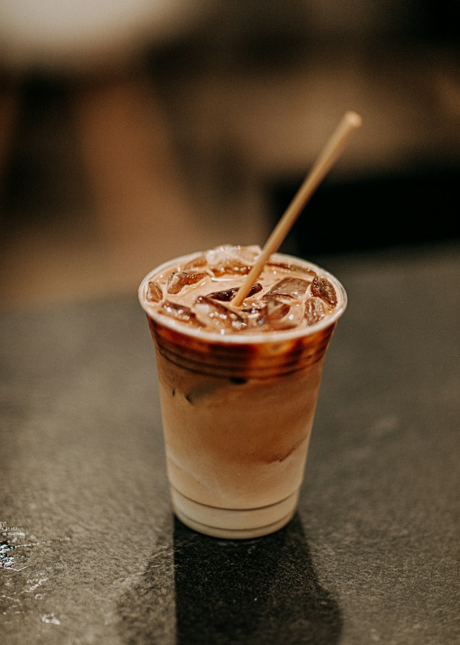 An iced latte in a clear takeaway cup with a paper straw