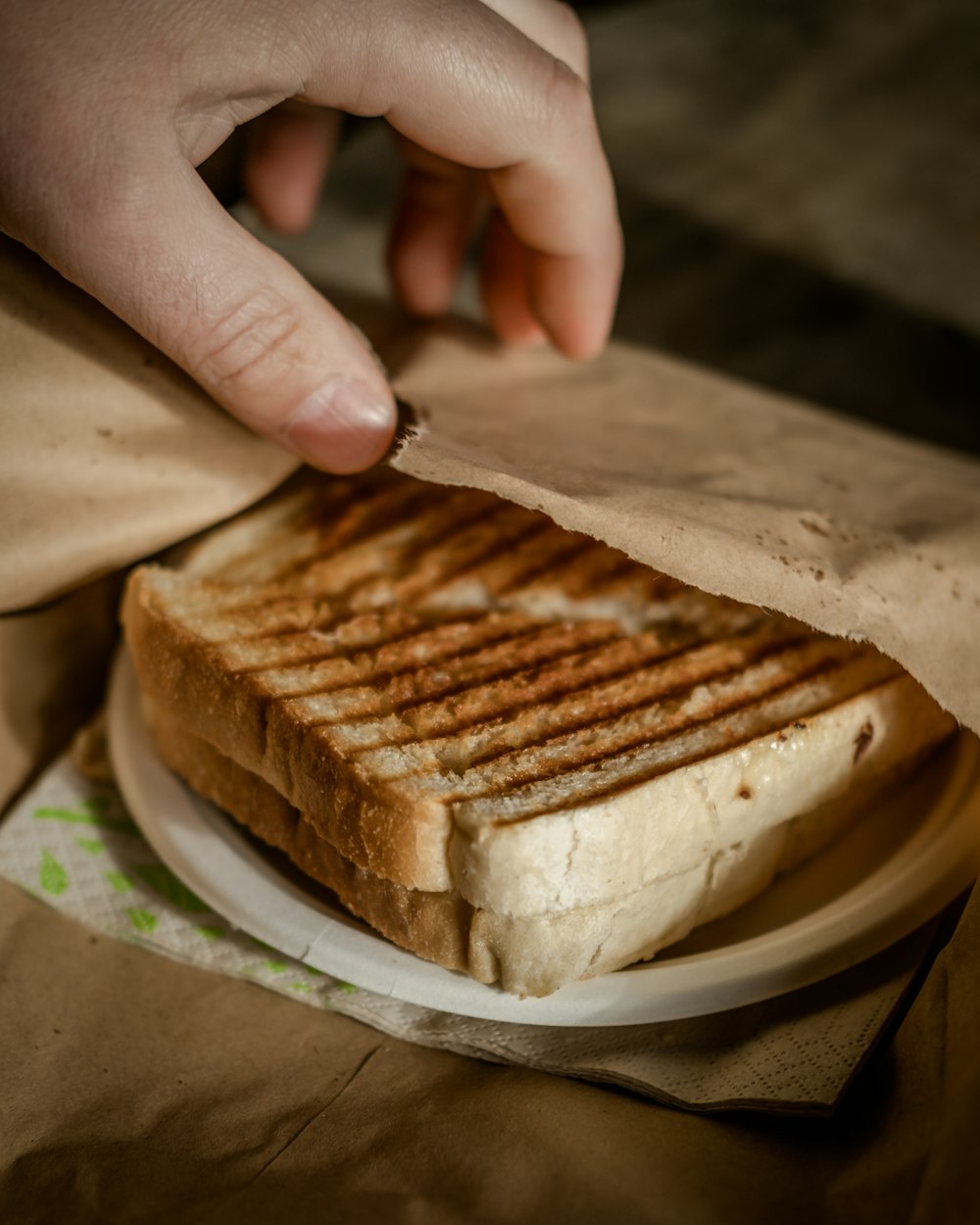 A grilled toastie being lifted out of a paper wrapper